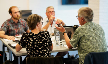 Fire sidder ved bord og arbejder med sognerapporten